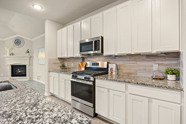 kitchen featuring stainless steel appliances, tasteful backsplash, white cabinets, and light stone counters