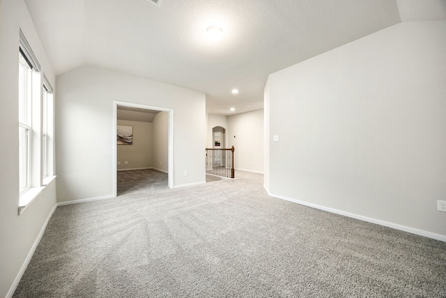 carpeted empty room with vaulted ceiling