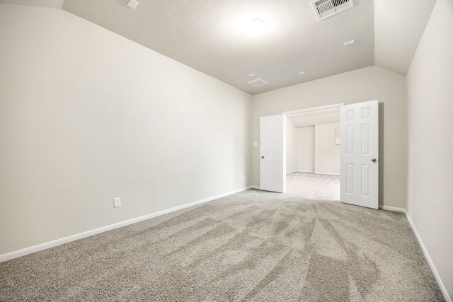 carpeted spare room with lofted ceiling and a textured ceiling