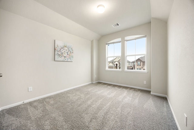 carpeted empty room with vaulted ceiling