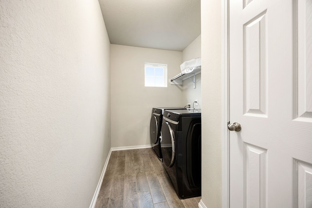 clothes washing area with washer and clothes dryer and light hardwood / wood-style flooring