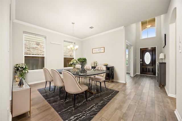 dining area with hardwood / wood-style flooring, ornamental molding, and a chandelier