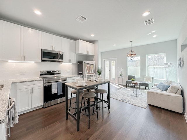 kitchen featuring pendant lighting, stainless steel appliances, dark hardwood / wood-style floors, light stone counters, and white cabinets