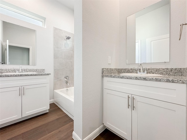 bathroom with hardwood / wood-style flooring, vanity, and tiled shower / bath combo