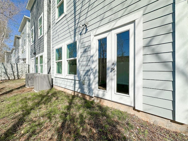 view of side of property featuring french doors, central AC, and a lawn