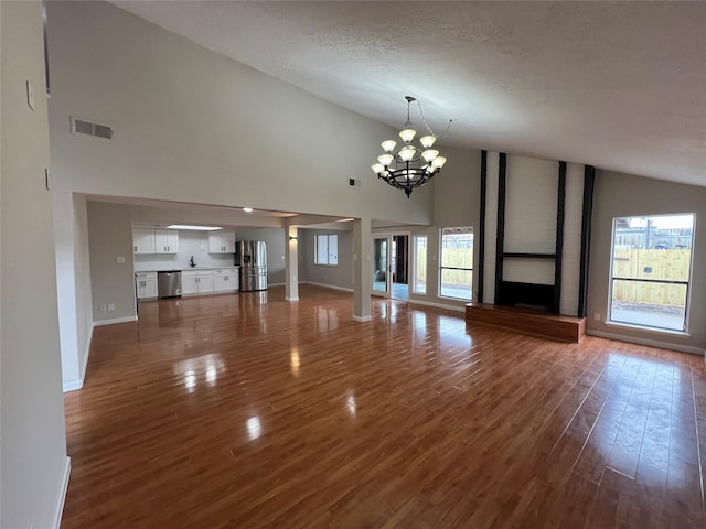 unfurnished living room with high vaulted ceiling, sink, dark hardwood / wood-style flooring, a notable chandelier, and a textured ceiling