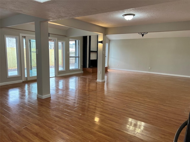 unfurnished living room with a healthy amount of sunlight, dark hardwood / wood-style flooring, and a textured ceiling