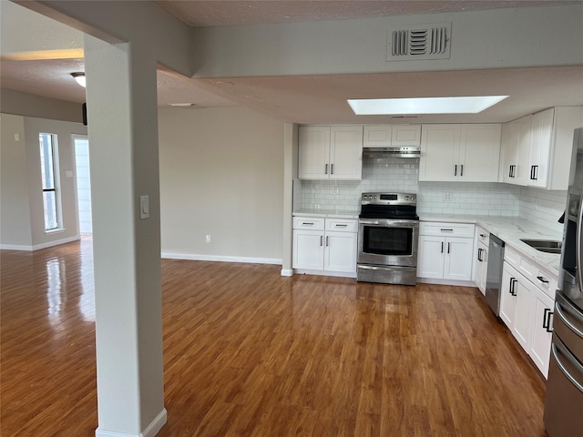 kitchen featuring wood-type flooring, a textured ceiling, stainless steel appliances, decorative backsplash, and white cabinets