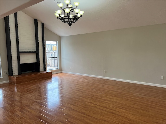 unfurnished living room featuring lofted ceiling, a notable chandelier, dark wood-type flooring, and a brick fireplace