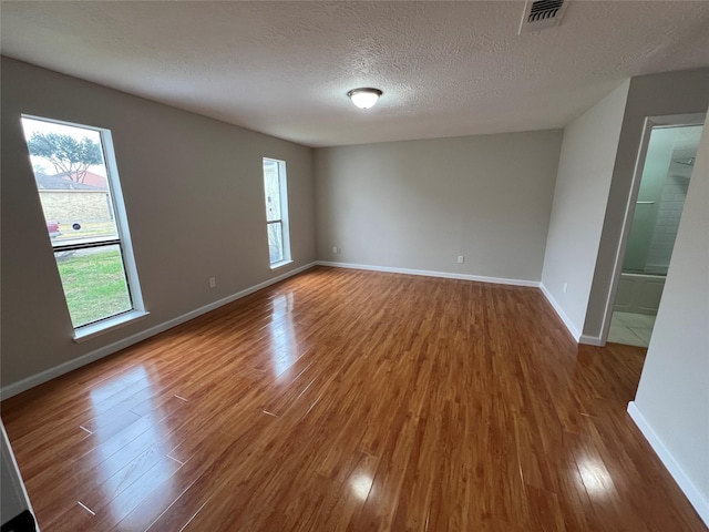 unfurnished room with a healthy amount of sunlight, dark hardwood / wood-style flooring, and a textured ceiling