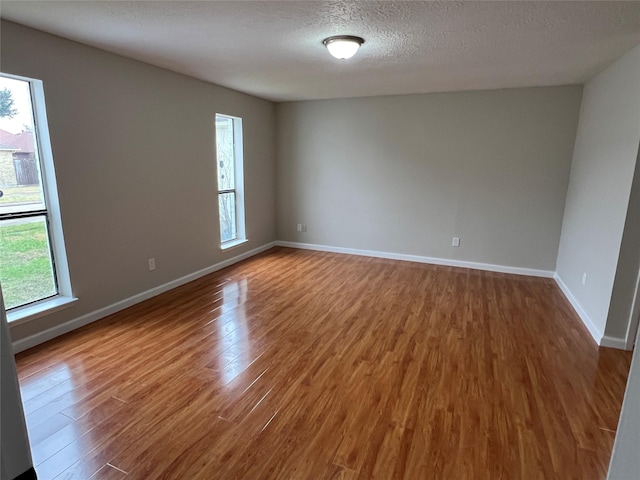 unfurnished room with hardwood / wood-style floors, a textured ceiling, and a wealth of natural light