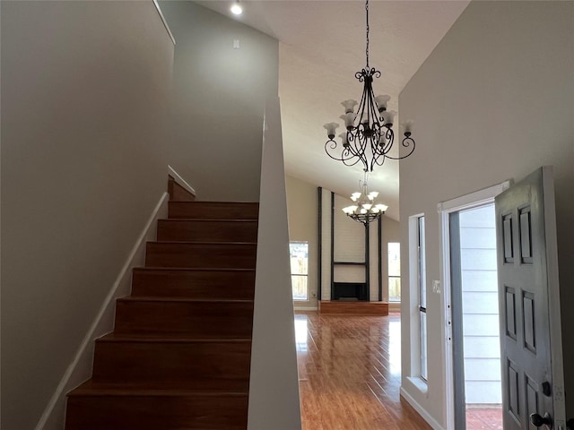 stairs featuring a towering ceiling, hardwood / wood-style floors, and a notable chandelier