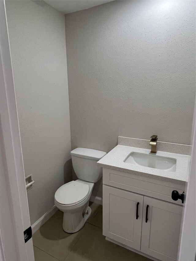 bathroom with tile patterned flooring, vanity, and toilet