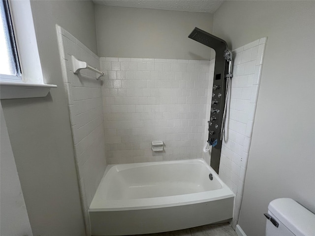 bathroom featuring tiled shower / bath combo and toilet