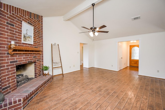 unfurnished living room featuring visible vents, lofted ceiling with beams, ceiling fan, wood finished floors, and a brick fireplace