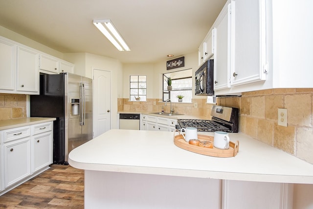 kitchen with stainless steel appliances, light countertops, a peninsula, and white cabinetry