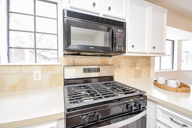 kitchen featuring light countertops, backsplash, white cabinets, black microwave, and stainless steel gas range oven