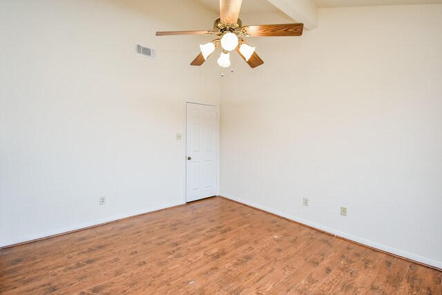 spare room with ceiling fan, beam ceiling, hardwood / wood-style floors, and a towering ceiling