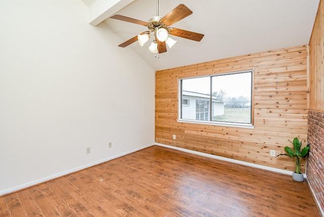 unfurnished room with lofted ceiling with beams, wood-type flooring, ceiling fan, and wooden walls