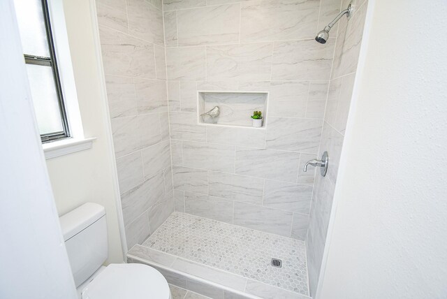 bathroom featuring a tile shower and toilet