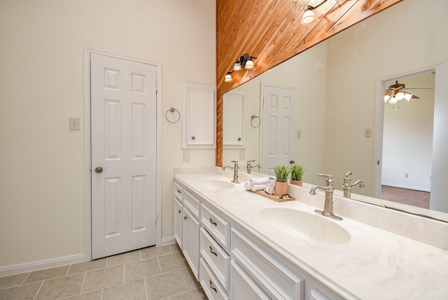 bathroom featuring double vanity, baseboards, a sink, and lofted ceiling