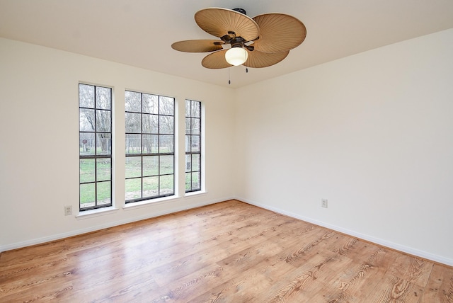 spare room featuring ceiling fan, light wood-style flooring, and baseboards