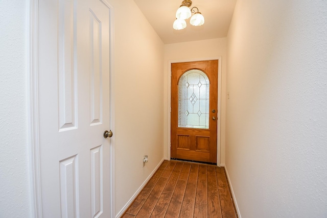 doorway to outside featuring a notable chandelier, baseboards, and wood finished floors