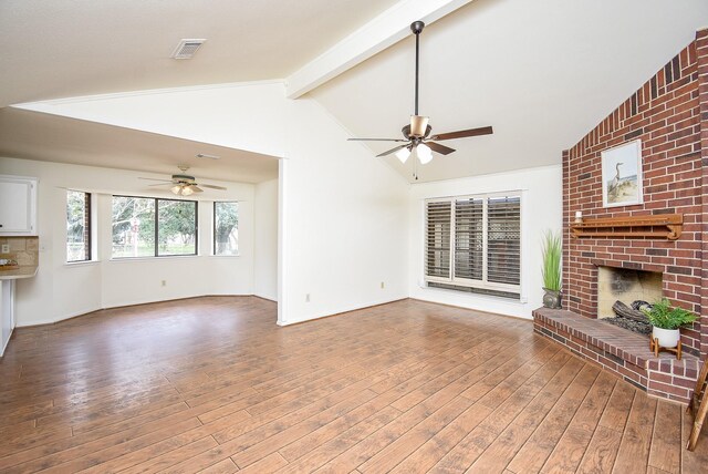 unfurnished living room with vaulted ceiling with beams, hardwood / wood-style flooring, a fireplace, and ceiling fan