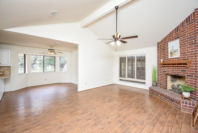 unfurnished living room with vaulted ceiling with beams, a fireplace, wood finished floors, visible vents, and a ceiling fan