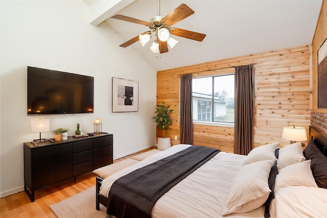 bedroom featuring wooden walls, a ceiling fan, baseboards, vaulted ceiling, and light wood-style floors