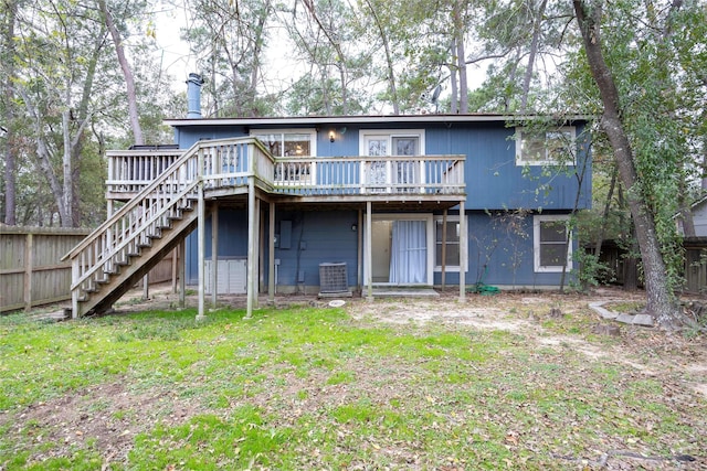 rear view of property with cooling unit, a wooden deck, and a lawn