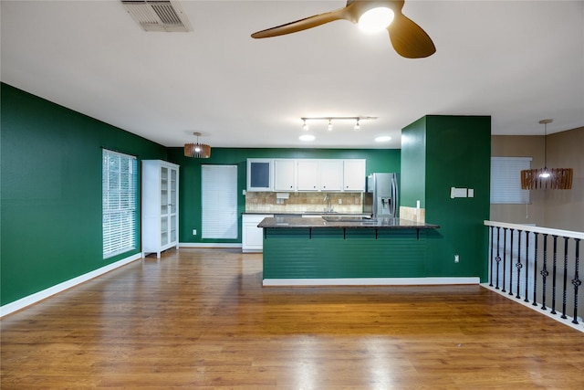 kitchen with white cabinetry, a breakfast bar, kitchen peninsula, and hanging light fixtures