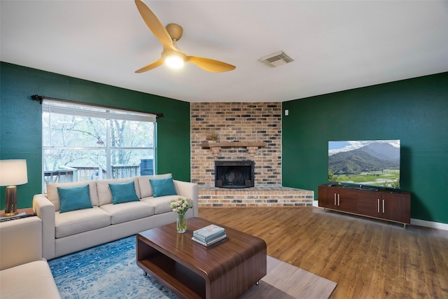 living room with ceiling fan, a fireplace, and wood-type flooring