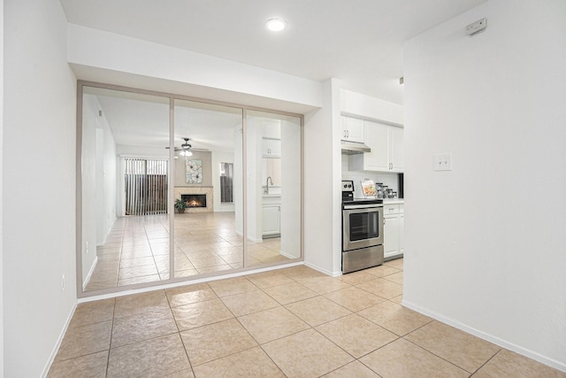 kitchen featuring ceiling fan, white cabinets, light tile patterned floors, and electric range