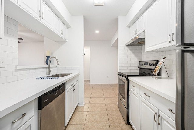 kitchen featuring sink, tasteful backsplash, light tile patterned floors, appliances with stainless steel finishes, and white cabinets