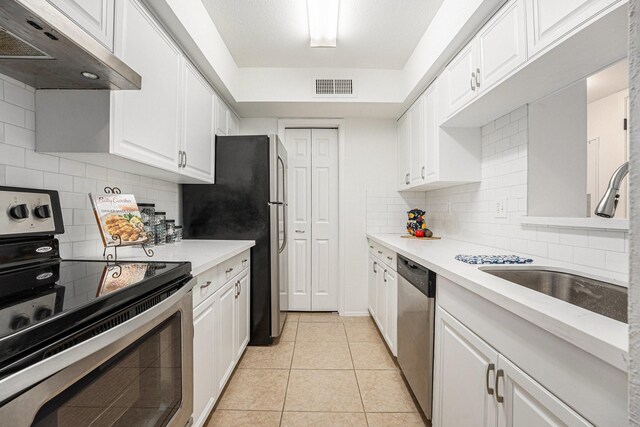 kitchen with light tile patterned flooring, sink, white cabinetry, tasteful backsplash, and appliances with stainless steel finishes