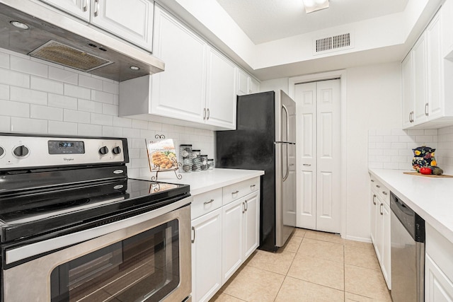 kitchen with stainless steel appliances, white cabinetry, light tile patterned floors, and backsplash