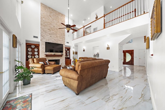 living room with a stone fireplace, a towering ceiling, and ceiling fan