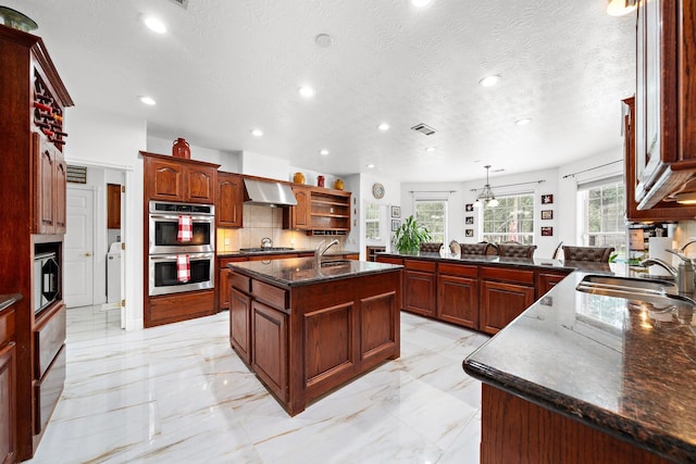 kitchen featuring sink, ventilation hood, a center island with sink, pendant lighting, and stainless steel appliances