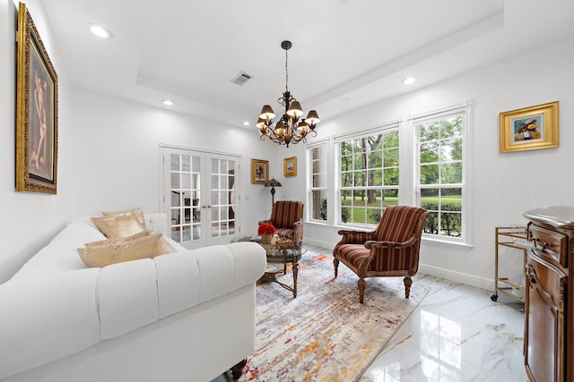 living room featuring french doors, a raised ceiling, and a chandelier