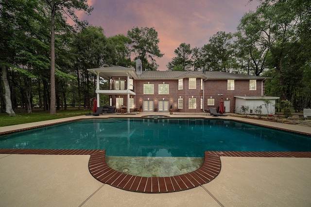 pool at dusk featuring a patio area