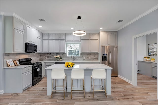 kitchen with a kitchen island, decorative backsplash, a kitchen bar, and black appliances