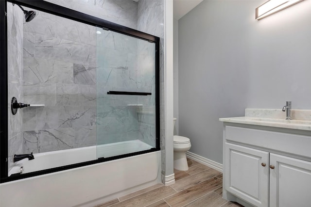 full bathroom with enclosed tub / shower combo, vanity, and toilet