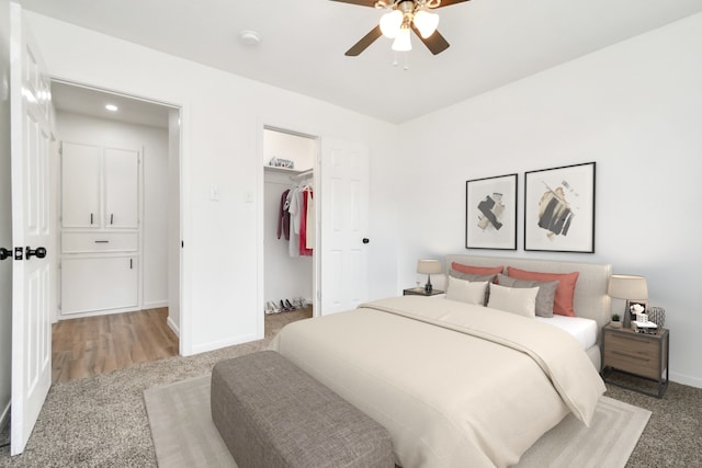 carpeted bedroom with a spacious closet, a closet, and ceiling fan