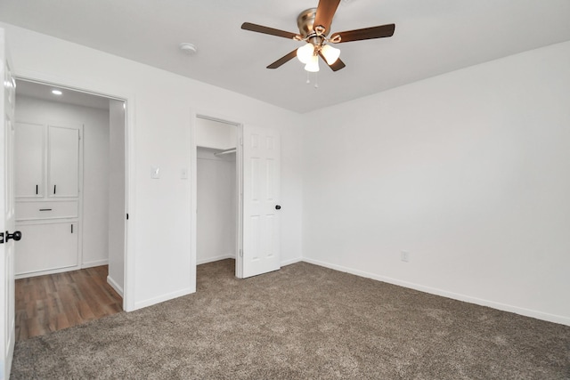 unfurnished bedroom featuring a walk in closet, carpet floors, ceiling fan, and a closet