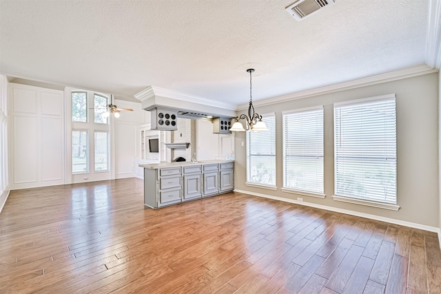 kitchen with decorative light fixtures, ceiling fan with notable chandelier, light hardwood / wood-style flooring, and a textured ceiling