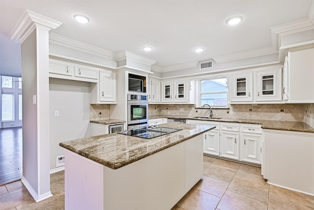 kitchen with a kitchen island, stone countertops, white cabinetry, sink, and stainless steel oven