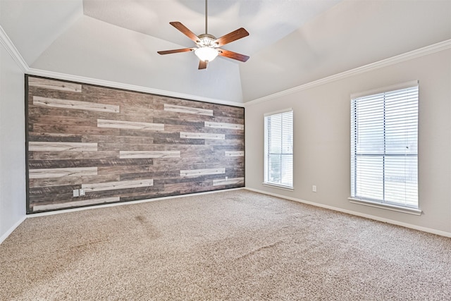 empty room with vaulted ceiling, ornamental molding, wooden walls, carpet flooring, and ceiling fan