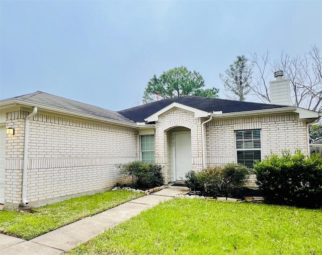 ranch-style house with a garage, brick siding, a front lawn, and a chimney