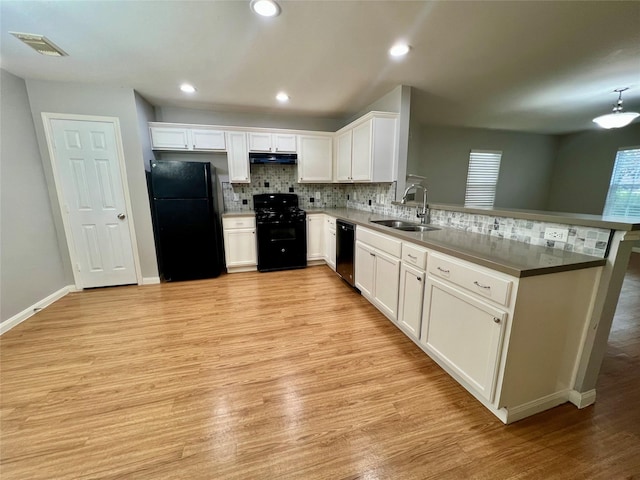 kitchen featuring under cabinet range hood, a sink, visible vents, white cabinetry, and black appliances